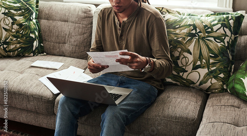 Paperwork, laptop and man sitting on sofa in home for finance, accounting and debt in living room. Computer, documents and online for insurance, bills and overdue payment with budget in apartment