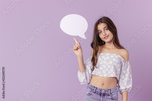 Photo of a winsome girl in a daisy print top holding a speech bubble, exhibiting empty space against a soft lavender background, different postures