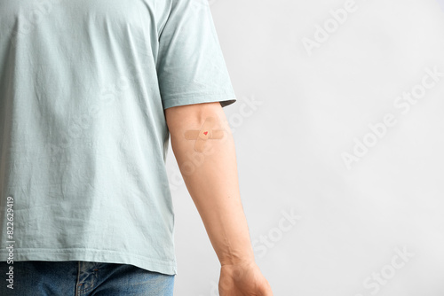 Blood donor with applied medical patch on grey background