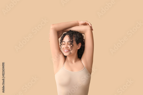 Beautiful young African-American woman on brown background