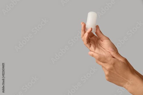 Female hands with deodorant on grey background