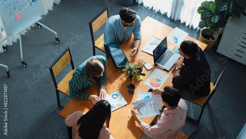 Skilled project manager walking at table while colleague brainstorm idea. Business team working together to plan marketing strategy while looking at data analysis or financial statistic. Convocation.