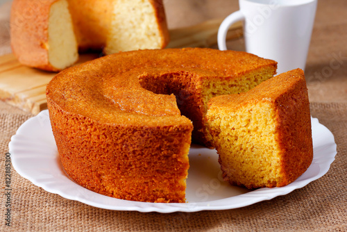 Homemade corn cake on white plate on rustic wooden table. Typical Brazilian party food.