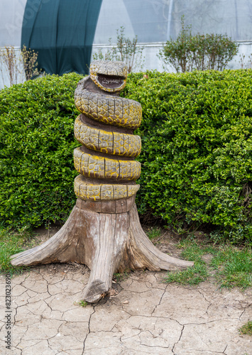 Wooden statue of snake wrapped around tree trunk.