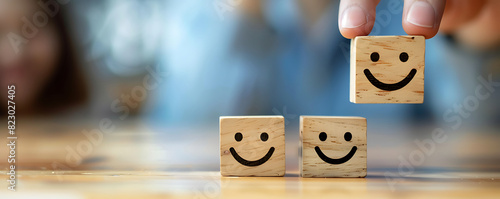 A person holding wooden blocks with smile face for positive customer review satisfaction feedback rating.