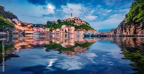 Illuminated old building of Vrbnik port reflected in the calm waters of Adriatic sea. Picturesque summer seascape of Krk island, Kvarner bay archipelago, Croatia, Europe. Travel the world..