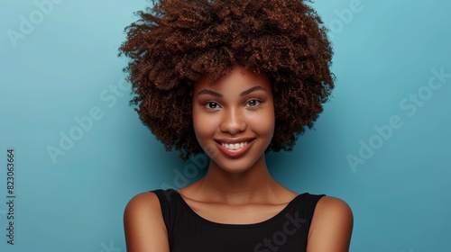  A smiling person in a black shirt and curly afro against a blue background