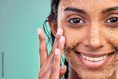 Studio portrait, woman and salt scrub for skincare with wellness, exfoliation and skin glow for facial. Indian girl, dermatology and sugar texture for face mask with vegan cosmetic by blue background