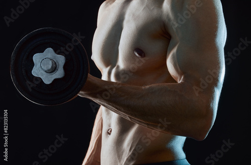 Healthy, man or athlete lifting dumbbell flexing in dark studio background for fitness, workout and wellness. Topless, bodybuilder or male person isolated and thinking of training and exercise