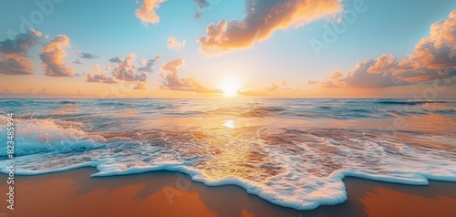 Tranquil beach scene at sunrise, with gentle waves lapping at the shore and the sky transitioning from night to day