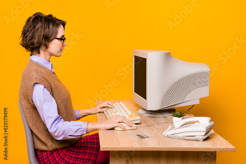 Photo portrait of attractive young woman sitting working computer dressed retro office clothes isolated on yellow color background