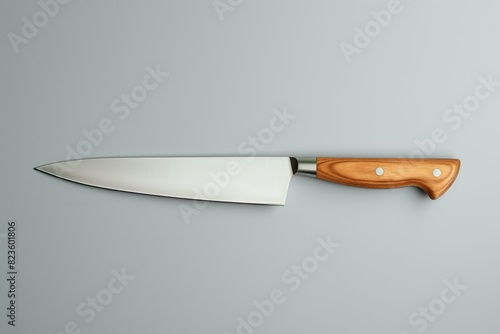 High-quality chef's knife with a polished wood handle and a sharp stainless steel blade, isolated on a grey background, depicting a culinary essential tool for cooking and food preparation