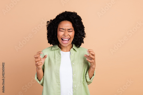 Photo of nice young woman closed eyes scream wear green shirt isolated on beige color background