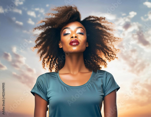 Fotografia de meio corpo de mulher negra, bonita, cabelos esvoaçantes, e céu claro ao fundo.
