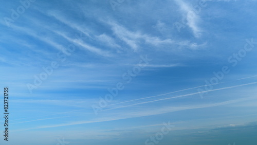 Clear blue sky with white wispy smoke clouds. Blue sky background with tiny stratus cirrus striped clouds. Timelapse.