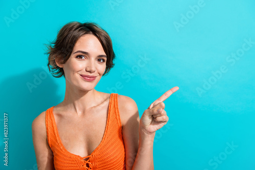 Photo of positive cheerful woman dressed knitwear singlet indicating at discount empty space isolated on turquoise color background