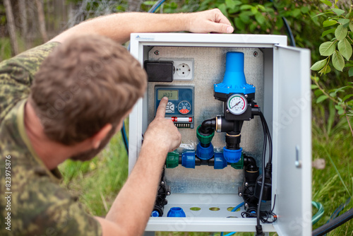 Setting up an automatic water supply system for drip irrigation. The man sets the watering time