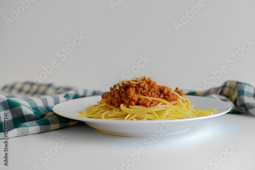 Spaghetti bolognese na białym talerzu, serwetka w biało-zieloną kratę