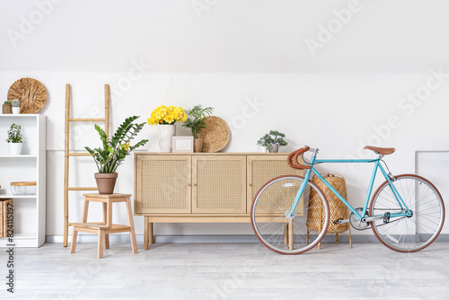 Interior of living room with bicycle and yellow narcissus flowers on wooden cabinet