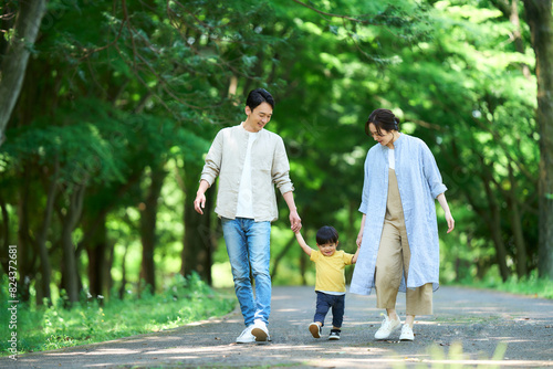 手を繋いで公園を歩く家族 