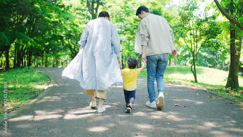 手を繋いで公園を歩く家族 