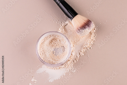 Glass jar with loose powder, swatch powder and makeup brush, applying powder on face on beige background. Concept of cosmetics , makeup. Top view.