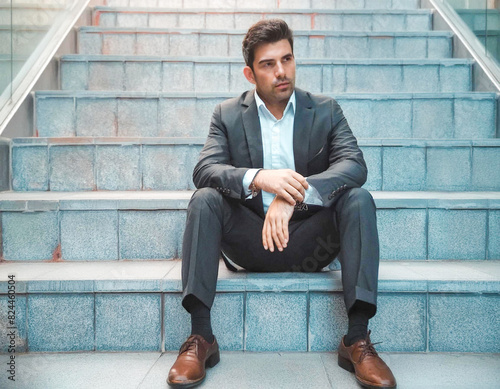 handsome man alone upset and worried businessman sitting on stairs after being laid off from job 