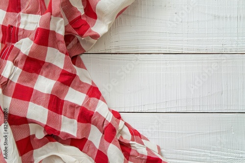 Photo of A blank linen napkin on top and red gingham fabric underneath, white wooden background. Web banner with copyspace in the right bottom corner