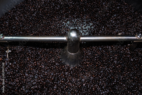 Close up of roasted coffee beans surface rotate in a spinning roaster mashine for background
