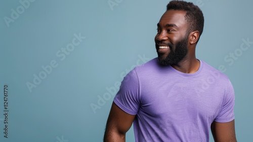 In this PNG, a young African American man with a beard wears a casual purple t-shirt and keeps his gaze turned to one side while smiling on his sleeve.