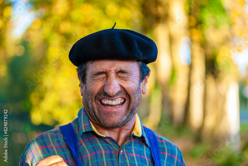 Portrait of a Frenchman, wearing a beret and blue dungarees smiling and gesticulating to camera