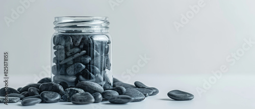 Clear glass jar with dark stones, placed on a white background to emphasize contrast