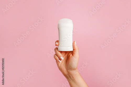 Hand holding white body deodorant on pink background