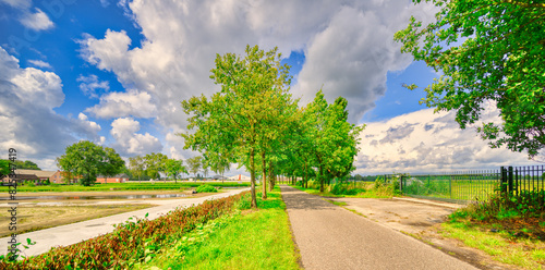 Country road in a rustic landscape in The Netherlands. Big clouds passing over.