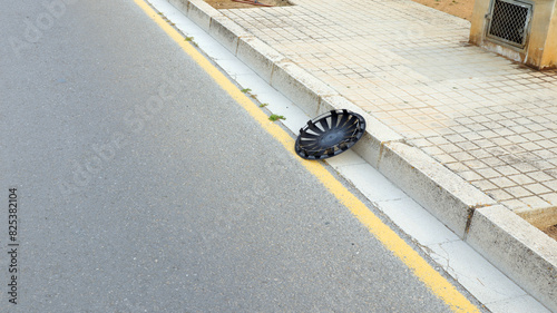 A lost hubcap from a car wheel lies on the side of the road.