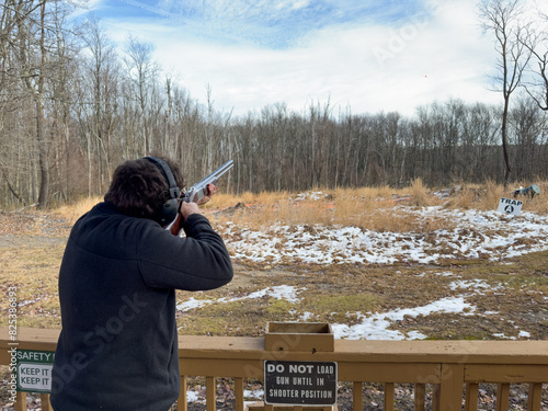 Young man shooting sporting clays with a shotgun at a shooting range