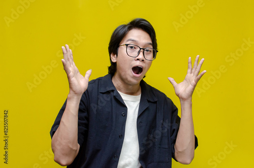 young asian man surprised with wow expression celebrating something. overjoyed young asian man shouting happily in possitive mood.