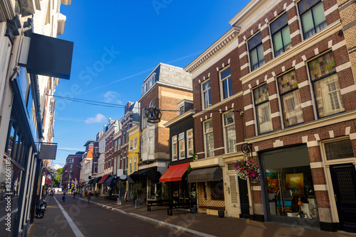 View of historical district of Old Town The Hague overlooking narrow picturesque street with old buildings, shops and open air restaurants on sunny summer day, Netherlands.