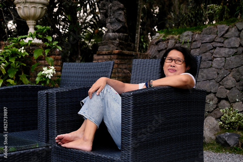 A woman sits comfortably in a rattan chair; smile a little