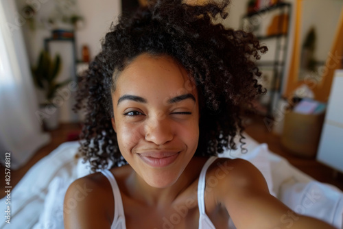 Realistic phone selfie made by beautiful african american winking smiling girl at home without filters