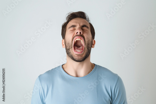 Young Man Yelling in Frustration with Intense Facial Expression on Grey Background