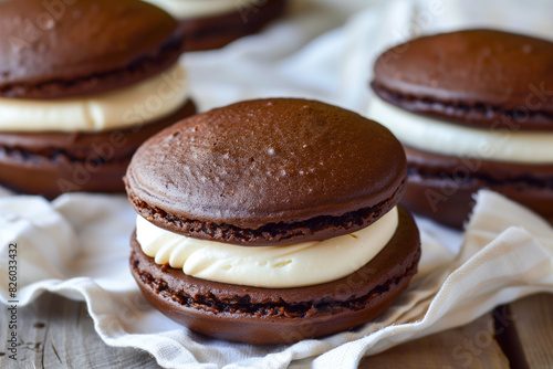 there are three chocolate macarons with cream filling on a napkin