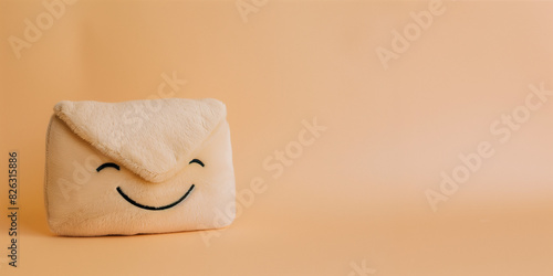 Cute smiling kawaii plushie envelope on a peach background with copy space