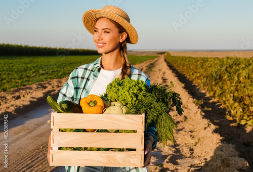 Young peasant woman carries box with organic vegetables