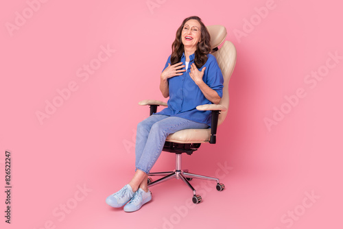 Full body photo of attractive retired woman sit armchair laugh dressed stylish blue clothes isolated on pink color background