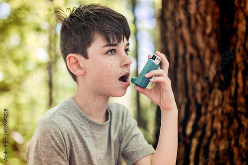 boy has an asthmatic agent in his hands in the park backgrounds. The boy in the white T-shirt with asthma inhaler.