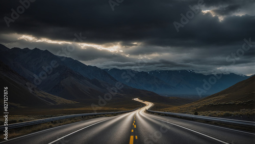 A long and winding road curves through a dark mountain pass.