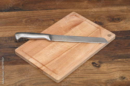 Srebrny nóż do pieczywa leży na drewnianej desce do krojenia, bez jedzenia, pusty