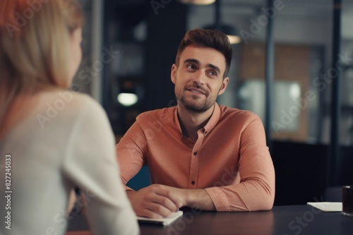 portrait of a handsome man leaning over the table talking to his female colleague at work