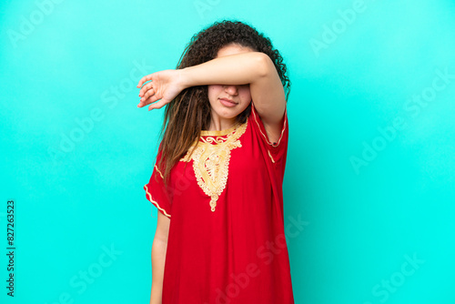 Young Arab woman isolated on blue background covering eyes by hands